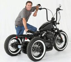 a man standing next to a black and white motorbike with wheels on it