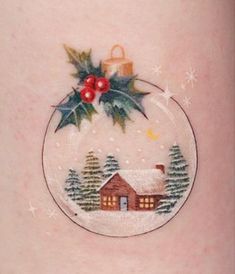 a christmas ornament on the back of a woman's thigh with holly and mist