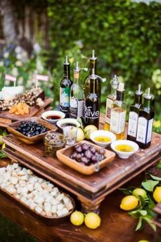 an assortment of food and wine on a table outdoors with lemons, grapes, nuts, and other foods