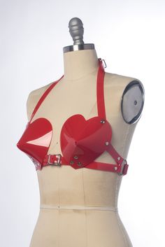 This bullet bra, or "cone bra" is inspired by retro pin-up vixens. This is the-heart-shaped version! Wear alone or layered and add a touch of drama to any outfit. Halter style straps. Buckles in front, back, and behind the neck. Silver-toned nickel plated hardware. Available in PVC, leather, and black vegan leather. Fits up to a DD cup - custom sizing available for larger cup sizes in leather, vegan leather, and clear PVC. Shown in white, clear, and red PVC (both translucent red and the new opaq Vinyl Skirt, Vinyl Skirting, Sticker Inspo, Vinyl Fashion, Leather Fits, Bullet Bra, Rave Bra, Body Adornment, Retro Pin Up