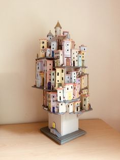 a small tower made out of buildings on top of a wooden table next to a wall