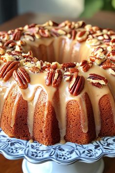 a bundt cake with frosting and pecans on top sitting on a plate