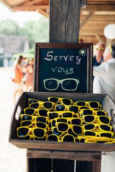 some yellow glasses are sitting in a box on a table with a sign that says serve yos