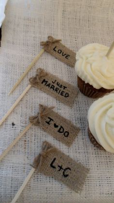 three cupcakes with white frosting and wooden sticks on a linen tablecloth