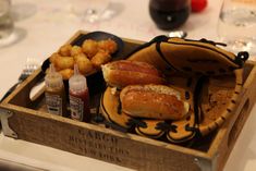 a wooden box filled with hot dogs and tater tots on top of a table