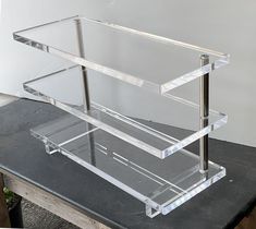 three tiered clear acrylic display case sitting on top of a black table