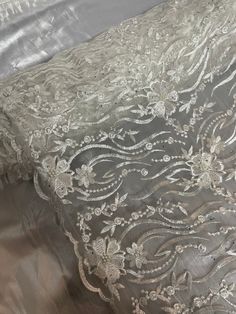 the fabric has been embroidered with white flowers and leaves on grey satin, while the material is