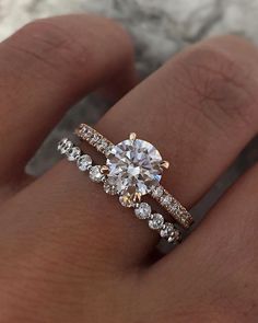 a woman's hand with two engagement rings on top of her finger, and the ring