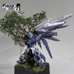 a model of a sci - fi character with wings on top of a table next to a tree