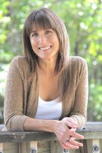 a woman sitting on a wooden bench with her arms crossed and smiling at the camera