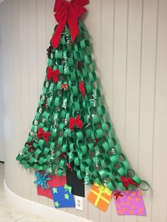 a christmas tree made out of green paper and red bows on the side of a wall