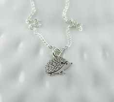 a silver necklace with a small hedgehog on it