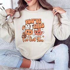 "Stay cozy in this super soft Occupational Therapy sweatshirt with retro Fall vibes. This Fall sweater features a cute retro cartoon pumpkin holding hands with a Fall leaf, with the inspirational phrase \"You've gOT this & I've gOT you\". Whether you're dressing up for your OT patients, or just want to get cozy and relax at home, you are sure to fall in love with this soft and comfy sweatshirt! Gildan 18000 Brand Sweatshirts  Unisex Adult Sizing Rolled Sleeves in pictures are for styling purpose Vintage Long Sleeve Tops With Cartoon Print, Retro Long Sleeve Sweatshirt With Cartoon Print, Cute Cartoon Print Fall Sweatshirt, Cute Cartoon Print Sweatshirt For Fall, Cute Orange Tops With Cartoon Print, Fun Fall Tops With Cartoon Print, Trendy Fall Sweatshirt With Character Print, Trendy Character Print Sweatshirt For Fall, Retro Long Sleeve Sweatshirt With Character Print