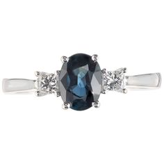 an oval blue and white diamond ring with three diamonds on the band, set in 18k white gold