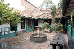 a courtyard with a fountain and benches in front of the building that has green shutters