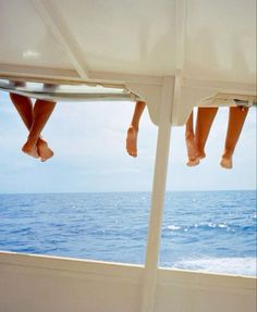 two people are hanging out on the back of a boat in the ocean, with their feet sticking out