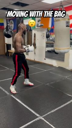 a man with no shirt is in the middle of a boxing ring holding a punching bag