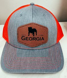 University Of Georgia, founded in 1785, it is one of the oldest public universities in the United States. This inspired us to create this original Georgia Design with the founded date and mascot on it. Cheer on the Dawgs to victory! Score a touchdown in style with the Georgia Bulldogs Leather Football Patch Hat! This unique hat features a laser engraved football pattern patch with a custom design, adding a playful touch to your game day outfit. Go Dawgs! Football Pattern, Patch Hat, Unique Hats, University Of Georgia, Gameday Outfit, Georgia Bulldogs, Purse Accessories, Laser Engraved, Bag Sale