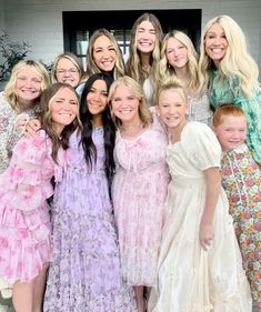 a group of young women standing next to each other in front of a door with their arms around each other