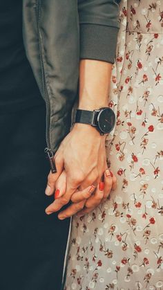 two people holding hands while standing next to each other on top of a floral print dress