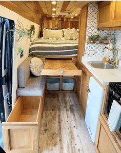 the interior of a camper with a bed, sink, and kitchen in it