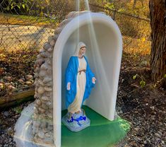 a statue of jesus is in the middle of a small tunnel with rocks surrounding it