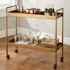 a gold bar cart with drinks and glasses on it