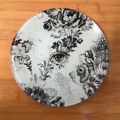 a black and white plate with an eye on the center is sitting on a wooden surface