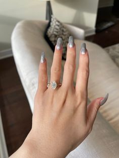 a woman's hand with silver and white nail polish holding a diamond ring on her finger