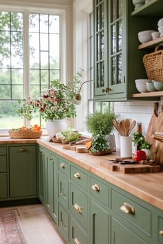 a kitchen filled with lots of green cupboards and counter top space next to a window