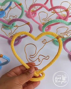 someone is holding up a crocheted heart with an elephant on it and the word love spelled in gold