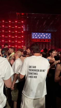 a group of people standing around each other in front of a red wall with neon lights