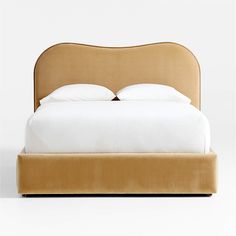 an upholstered bed with white sheets and pillows on the headboard is shown