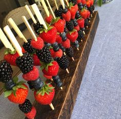 strawberries and blackberries are arranged on skewers