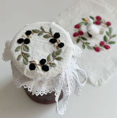 two embroidered coasters sitting next to each other on top of a white tablecloth