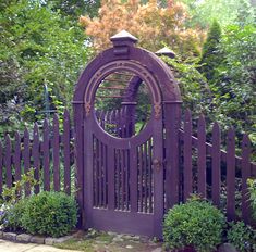 an iron gate surrounded by bushes and trees