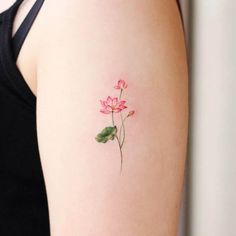 a woman's arm with a small pink flower tattoo on the left side of her body