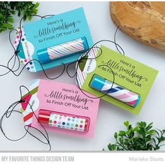 three different types of pens and magnets on a white surface with greenery in the background