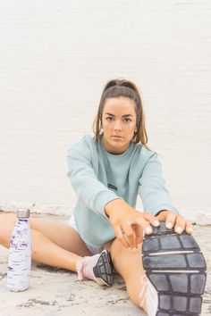 a young woman sitting on the ground with her foot up next to a water bottle