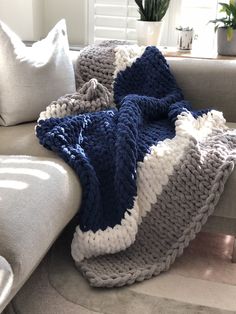 a crocheted blanket sitting on top of a couch next to pillows and a potted plant