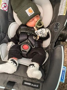 a baby in a car seat wearing a hat