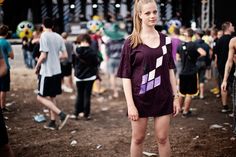 a young woman standing in front of a crowd at a music festival wearing a purple dress