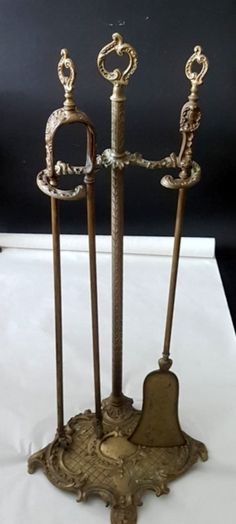 three ornate metal candlesticks on display with white table cloth and black wall in background