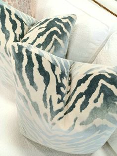 two pillows sitting next to each other on top of a white couch with zebra print