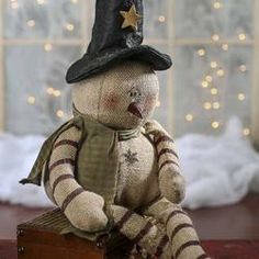 a teddy bear wearing a hat and scarf sitting on top of a wooden box in front of a christmas tree