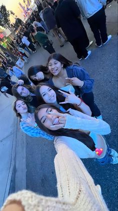 a group of young women standing next to each other on a city street with their hands in the air