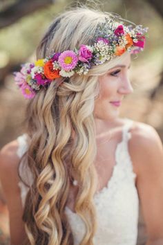 a girl with flowers in her hair is looking at the camera and she has long blonde hair