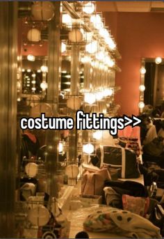 a room filled with lots of clothes and lights next to a mirror that says costume fittings >