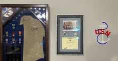 a display case with an army uniform hanging on the wall next to a us navy plaque