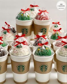 many starbucks cups are wrapped in plastic and have red bows on them, with chocolate covered desserts inside